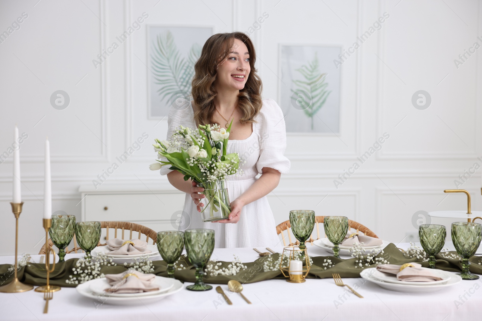 Photo of Happy young woman setting table for dinner at home