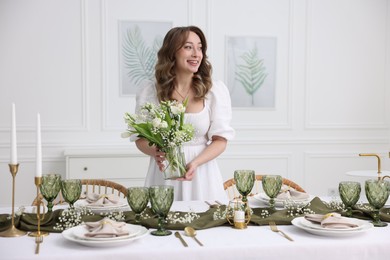 Happy young woman setting table for dinner at home