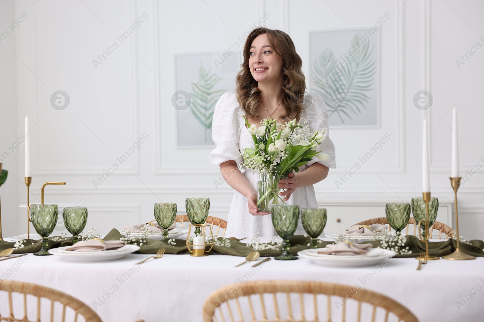 Photo of Happy young woman setting table for dinner at home