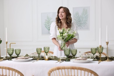 Photo of Happy young woman setting table for dinner at home