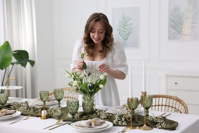 Photo of Happy young woman setting table for dinner at home