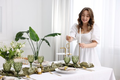 Photo of Happy young woman setting table for dinner at home