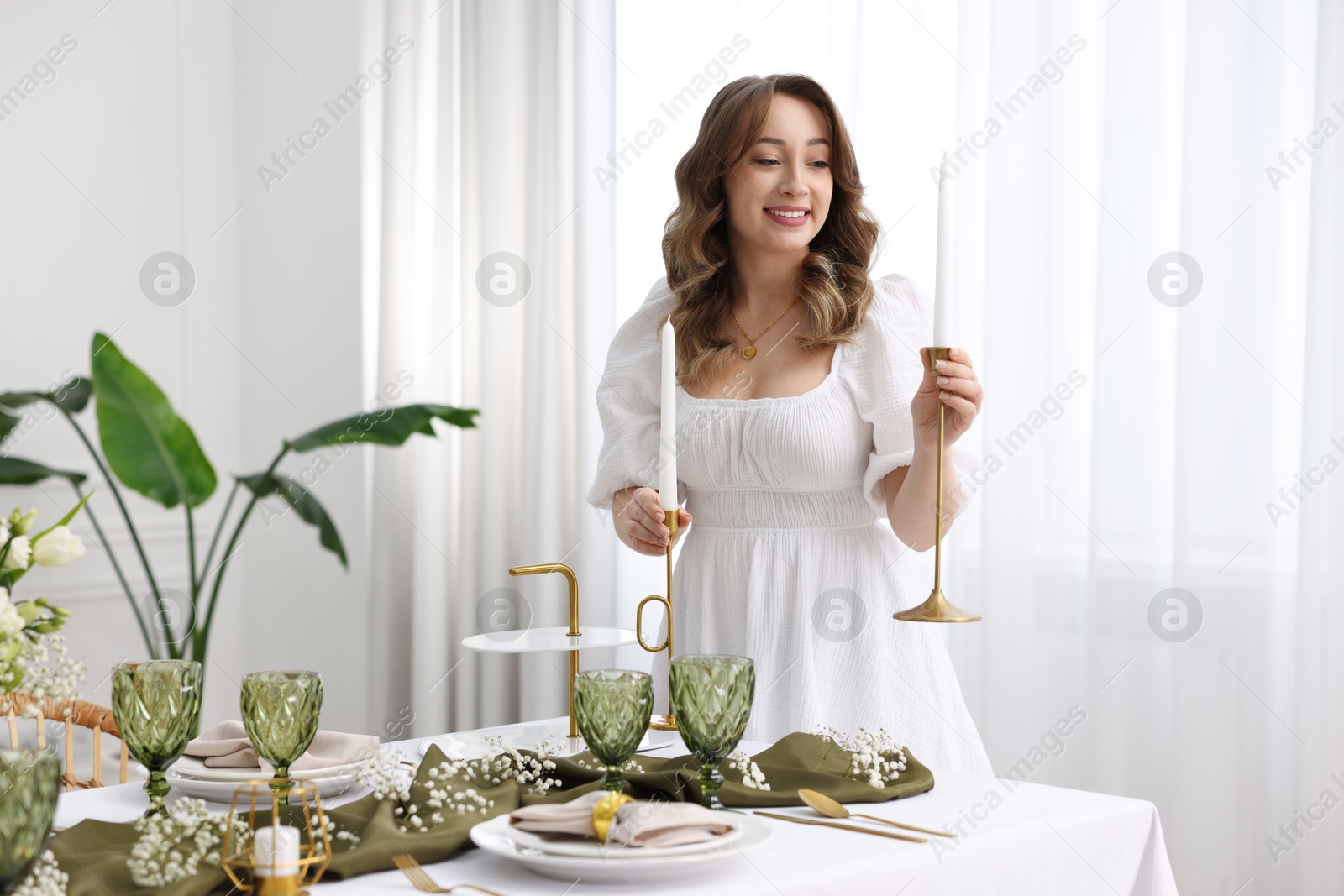 Photo of Happy young woman setting table for dinner at home