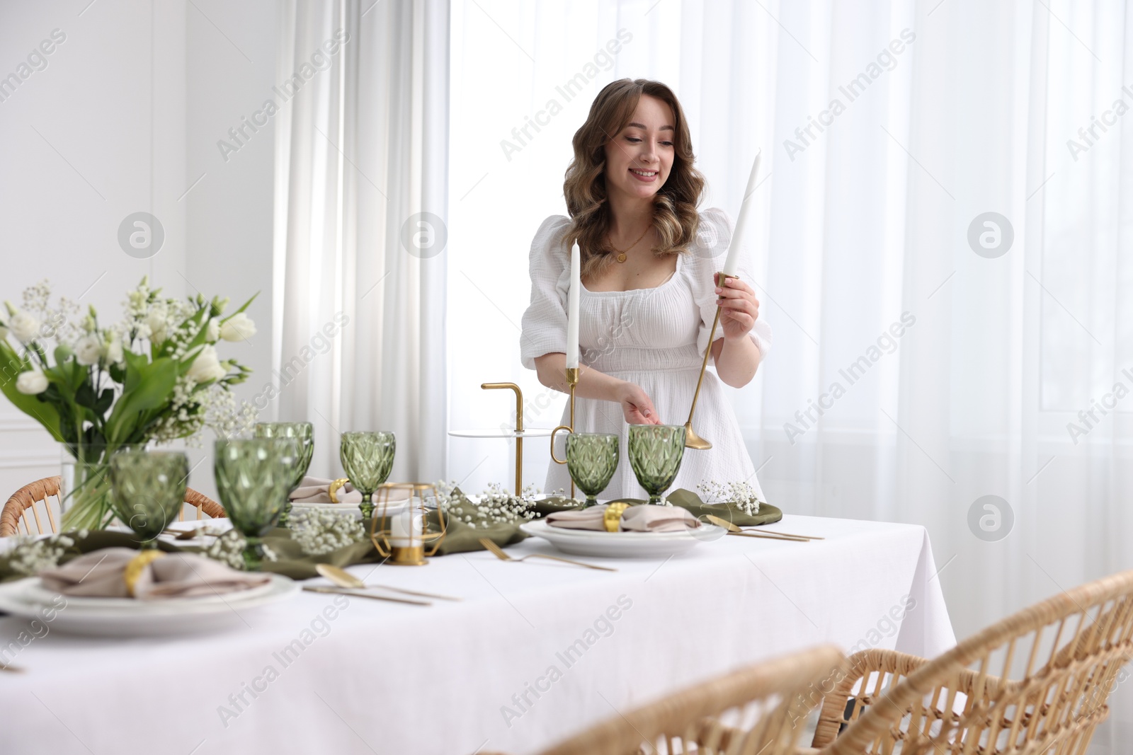 Photo of Happy young woman setting table for dinner at home