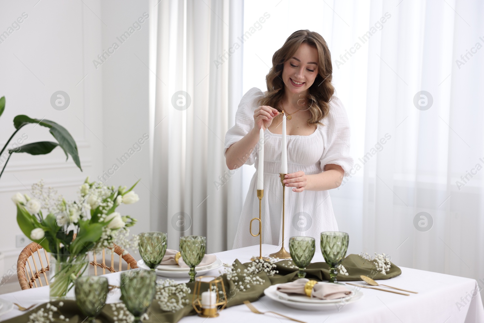 Photo of Happy young woman setting table for dinner at home