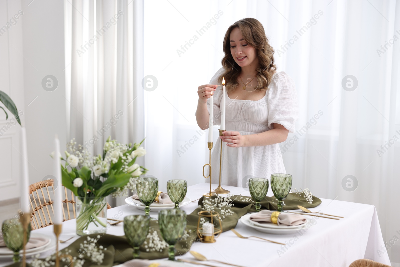 Photo of Happy young woman setting table for dinner at home