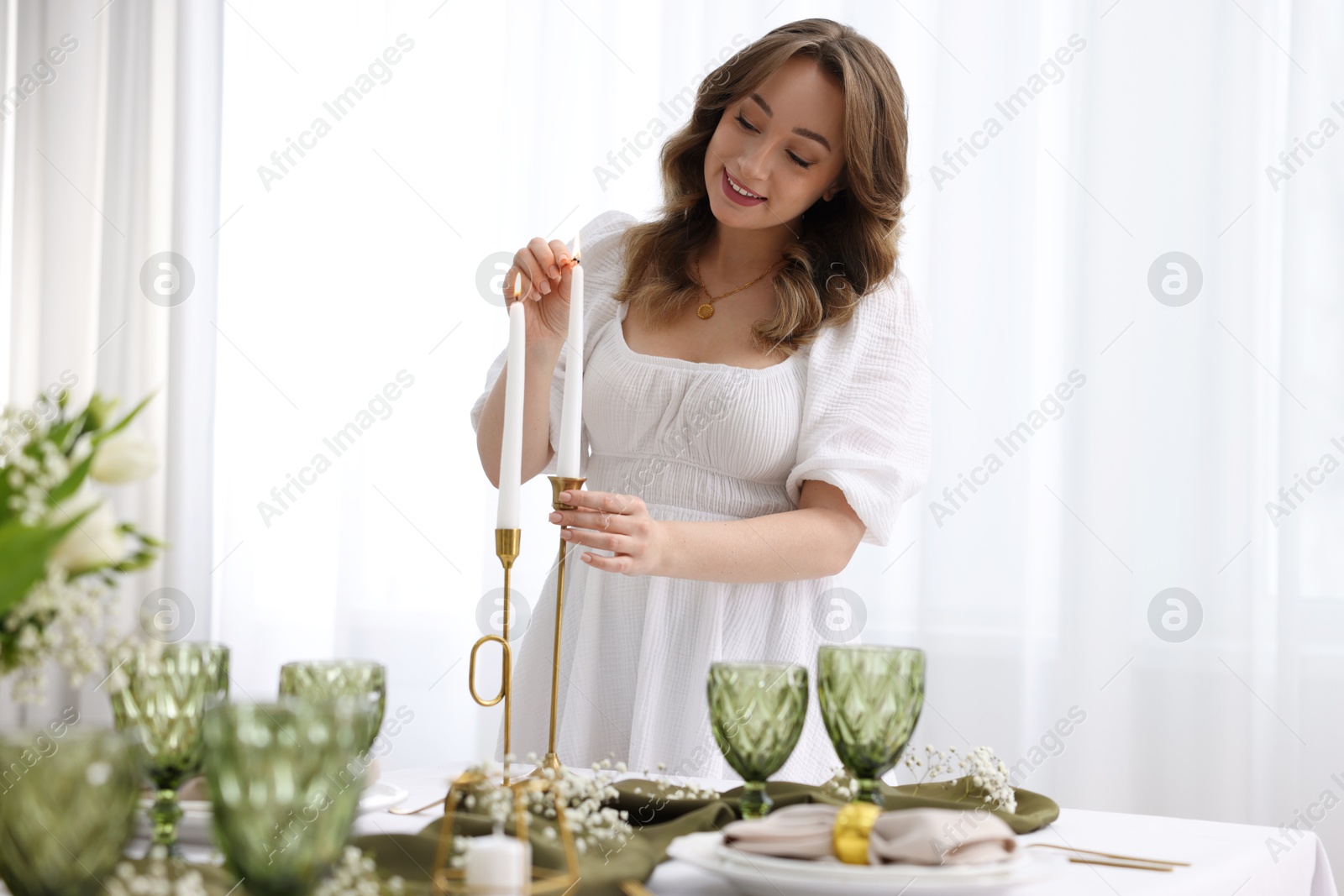 Photo of Happy young woman setting table for dinner at home