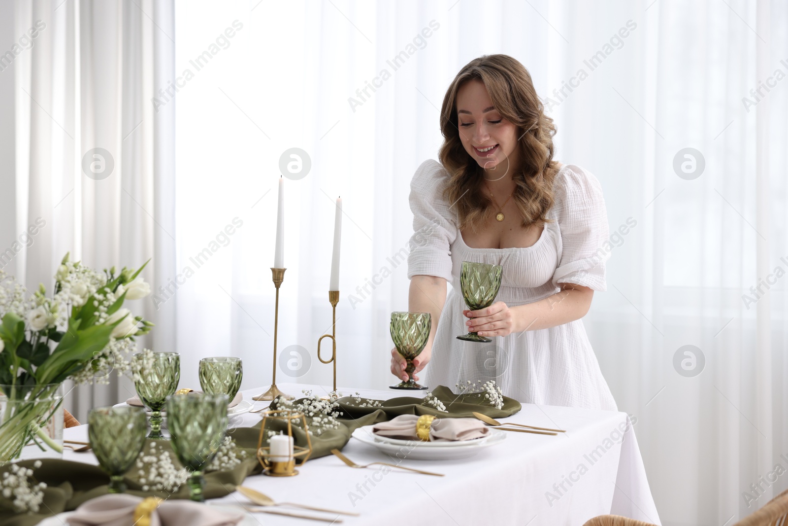 Photo of Happy young woman setting table for dinner at home