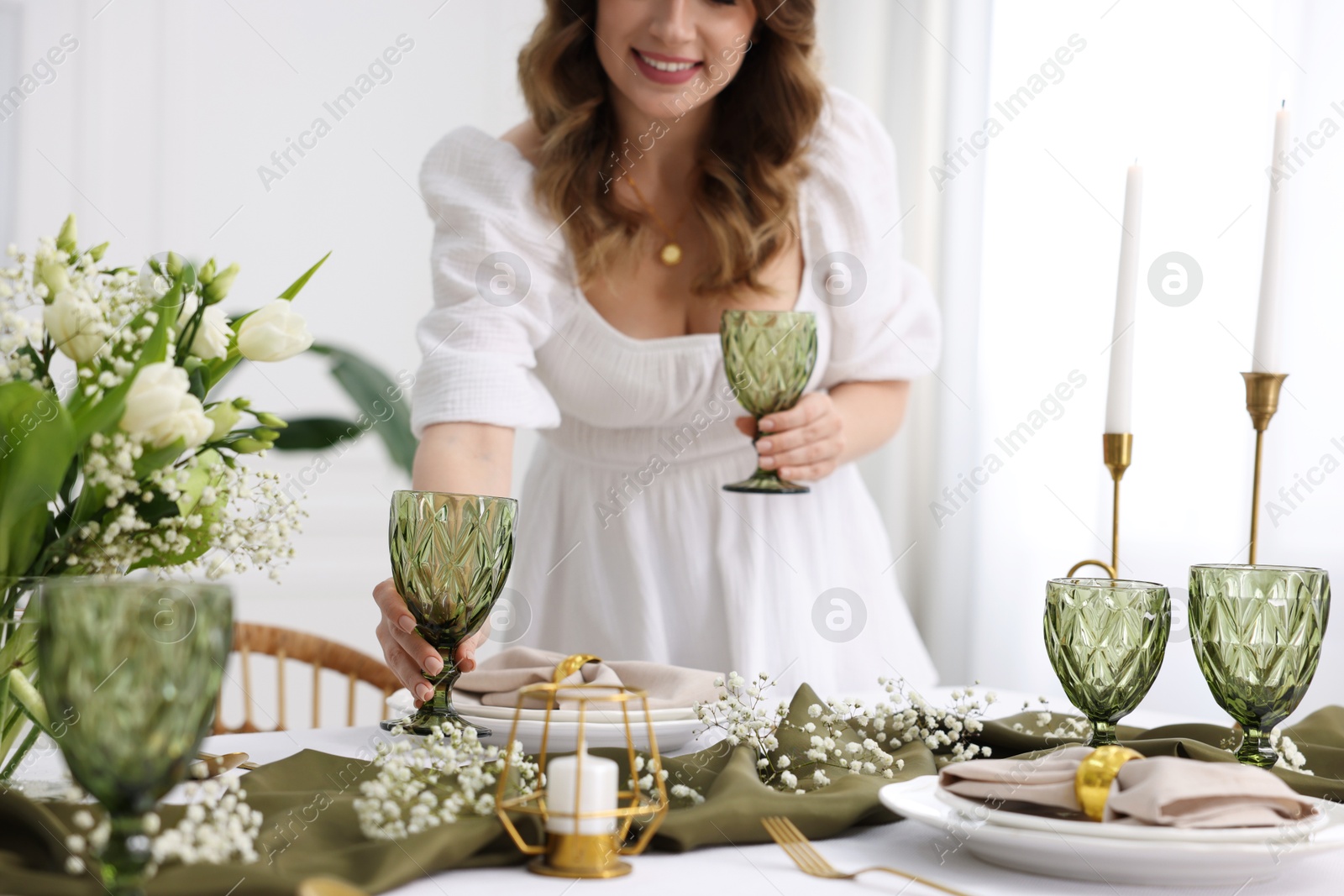 Photo of Happy young woman setting table for dinner at home, selective focus