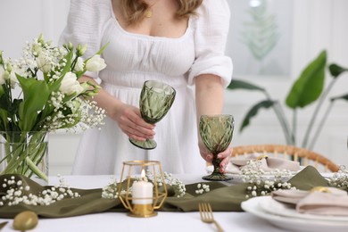 Young woman setting table for dinner at home, closeup