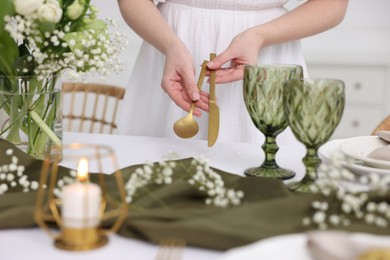 Young woman setting table for dinner at home, closeup