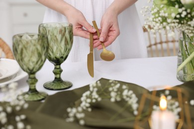 Young woman setting table for dinner at home, closeup