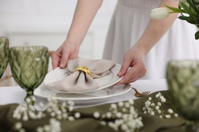 Young woman setting table for dinner at home, closeup