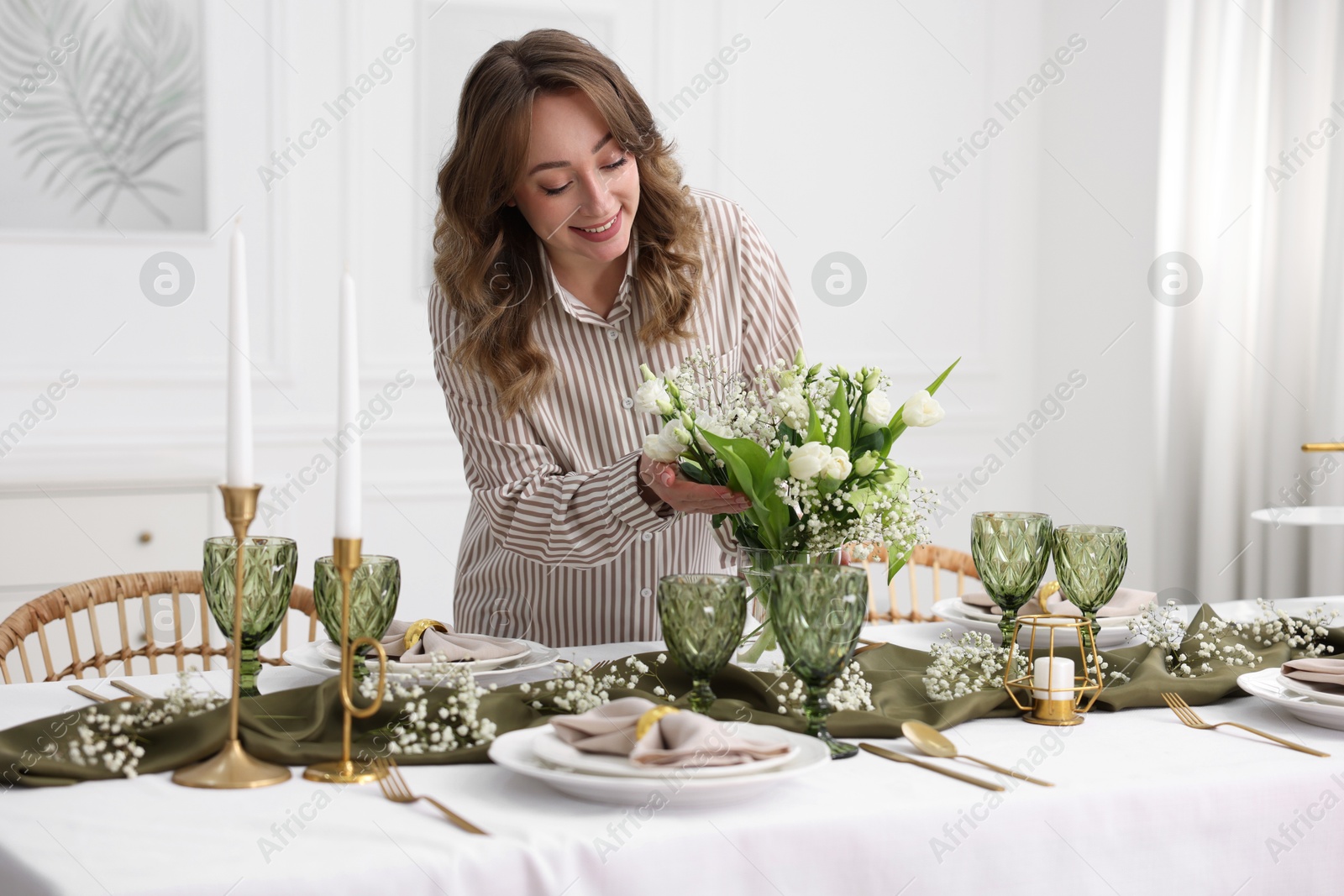 Photo of Happy young woman setting table for dinner at home