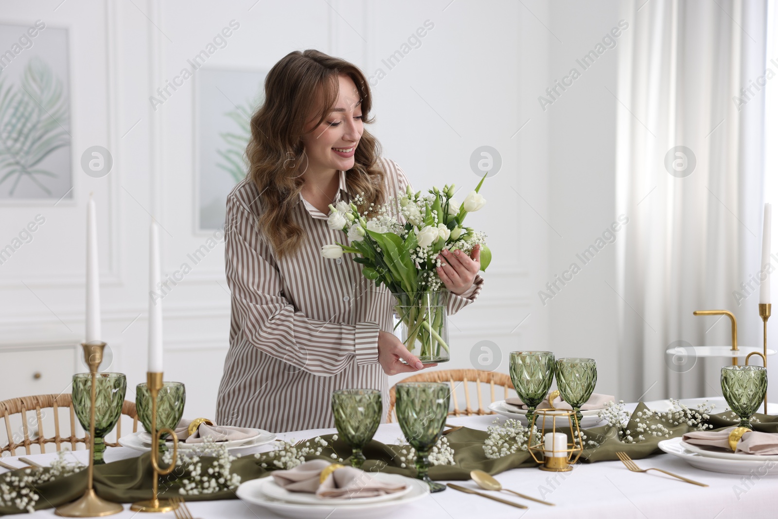 Photo of Happy young woman setting table for dinner at home