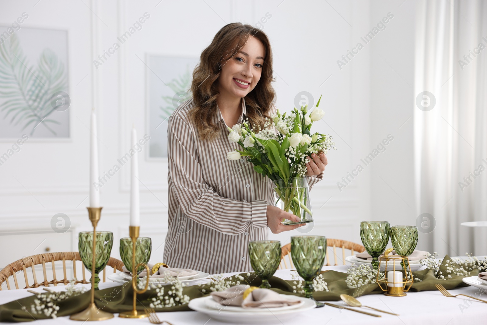 Photo of Happy young woman setting table for dinner at home