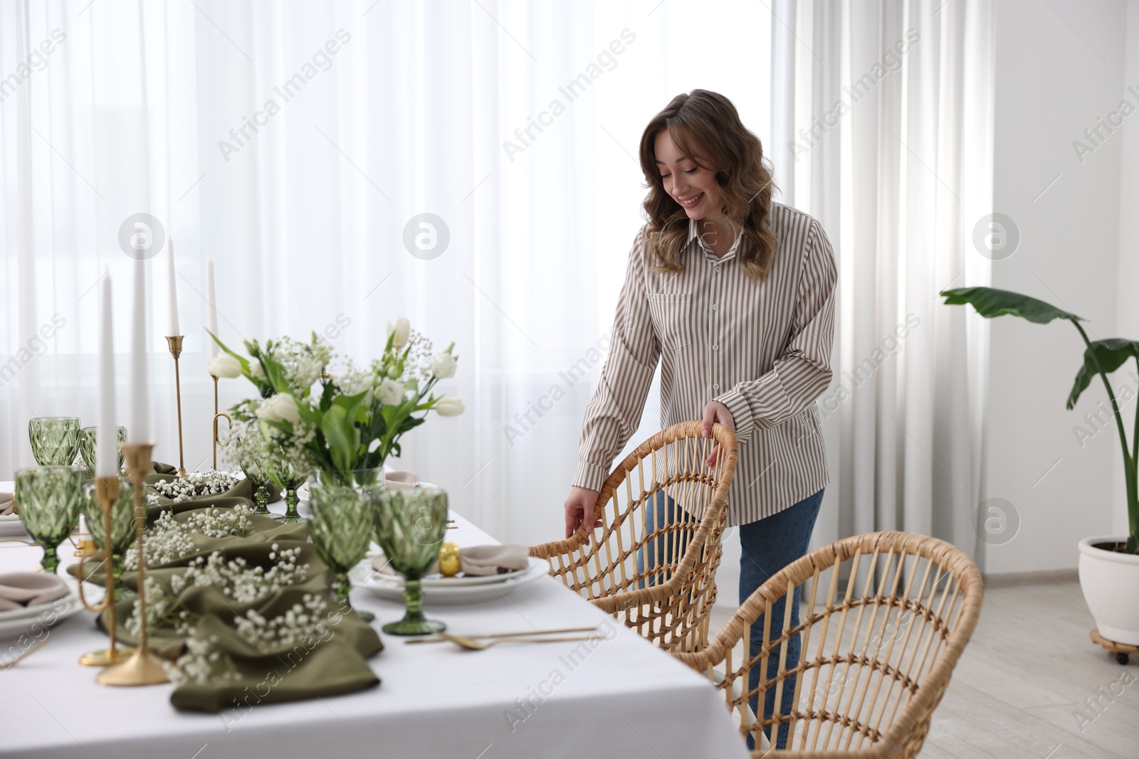 Photo of Happy young woman setting table for dinner at home