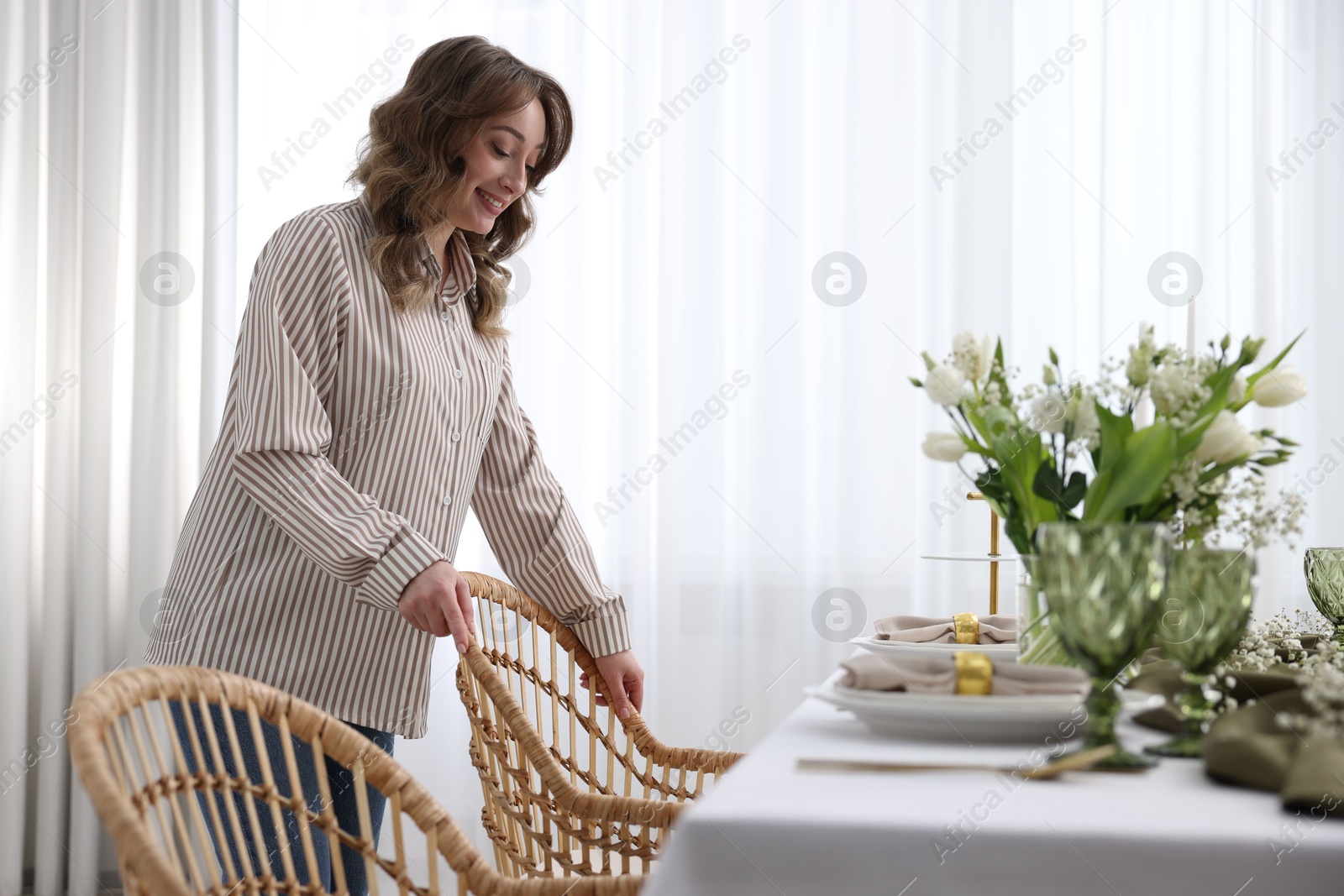 Photo of Happy young woman setting table for dinner at home