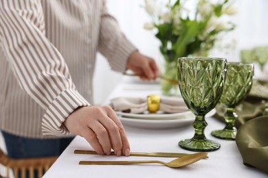 Young woman setting table for dinner at home, closeup