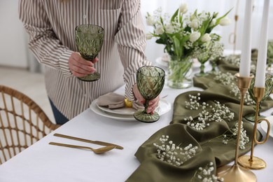 Young woman setting table for dinner at home, closeup