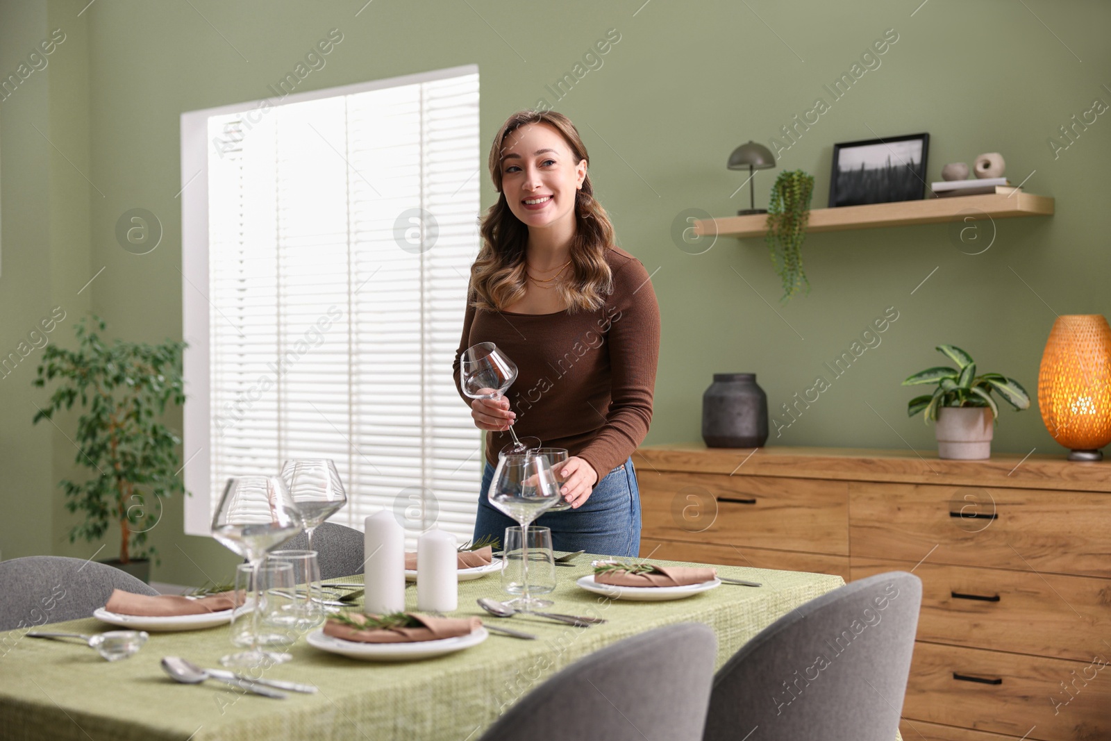 Photo of Happy young woman setting table for dinner at home