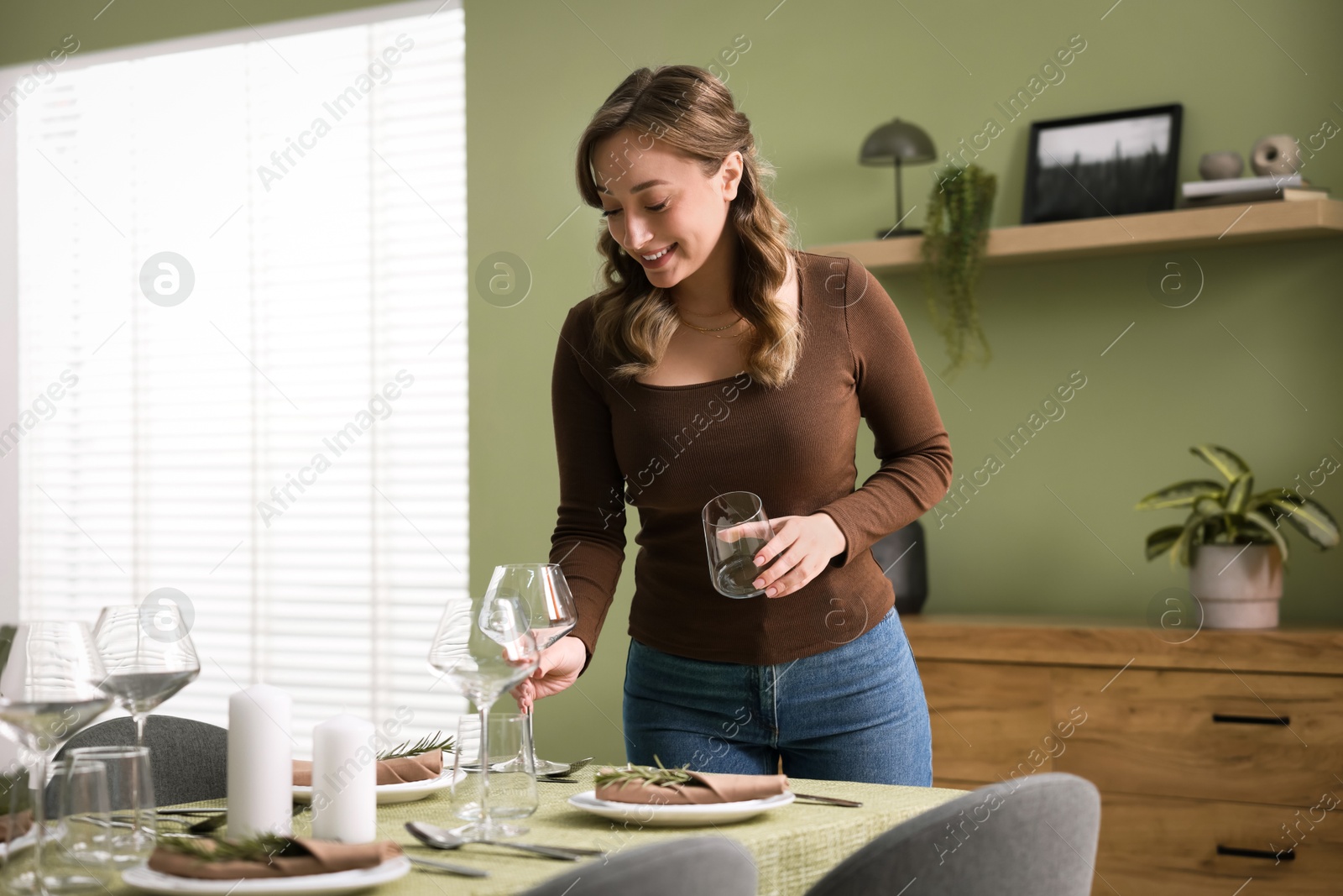 Photo of Happy young woman setting table for dinner at home