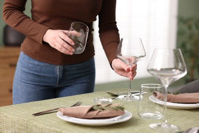 Photo of Young woman setting table for dinner at home, closeup