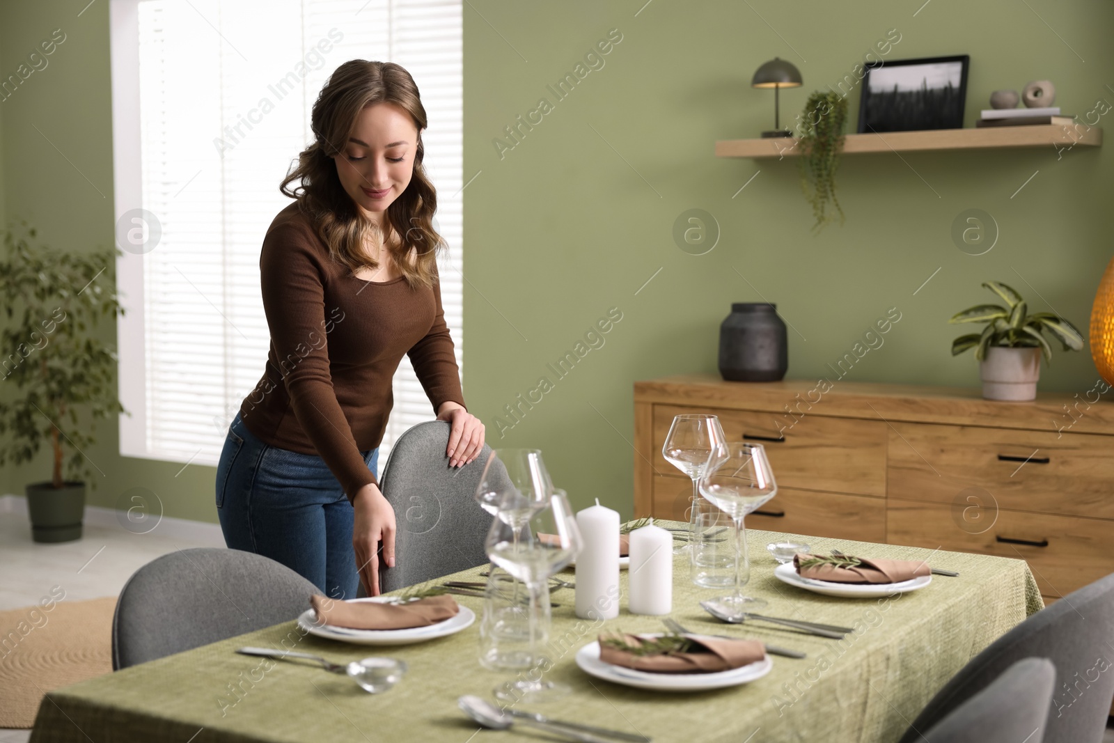 Photo of Young woman setting table for dinner at home