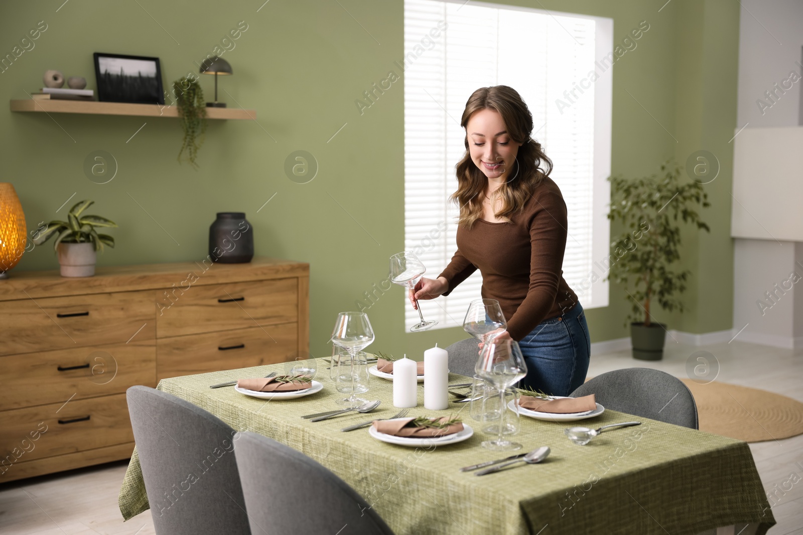 Photo of Happy young woman setting table for dinner at home