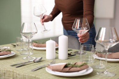 Young woman setting table for dinner at home, closeup