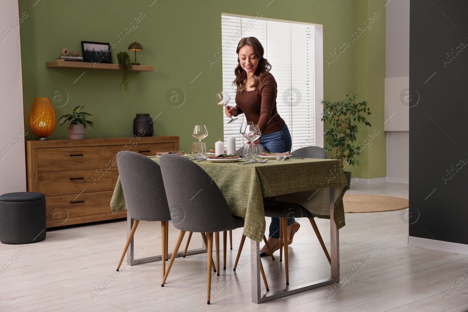 Photo of Happy young woman setting table for dinner at home