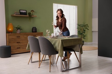 Photo of Happy young woman setting table for dinner at home