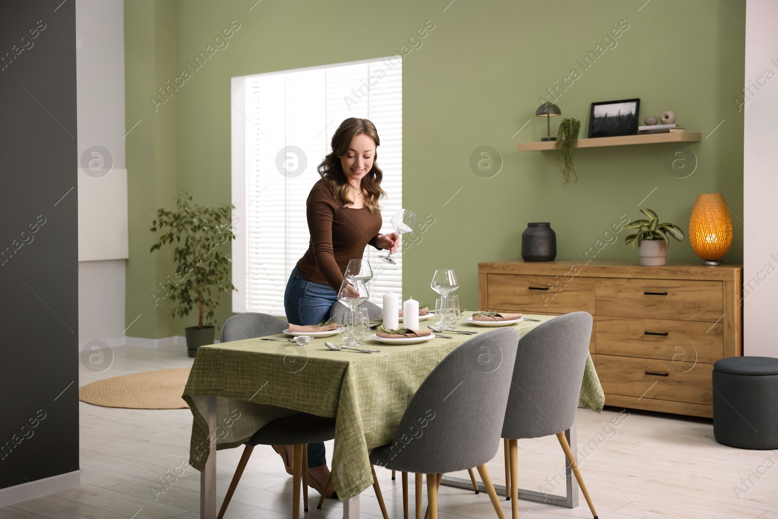 Photo of Happy young woman setting table for dinner at home