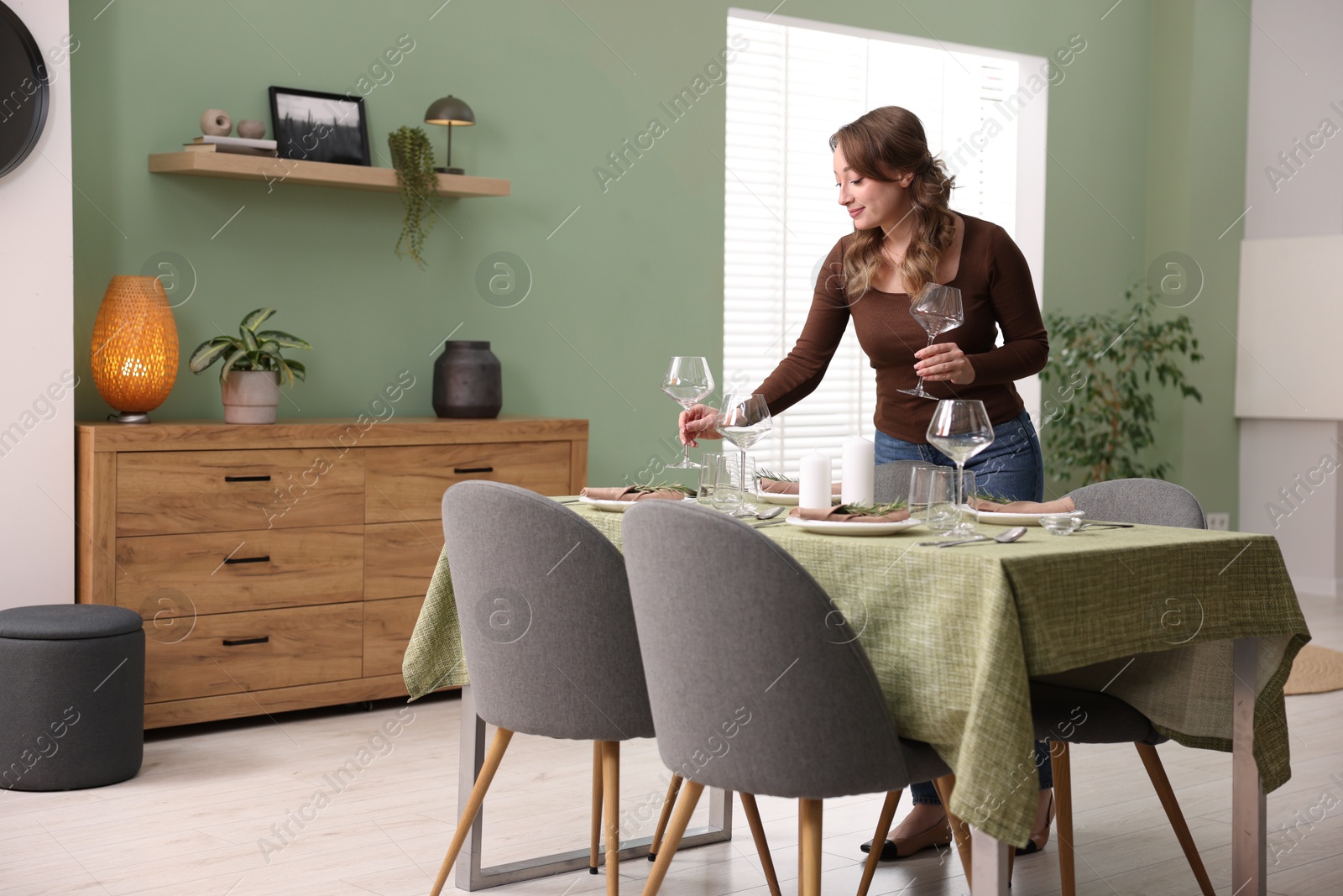 Photo of Young woman setting table for dinner at home