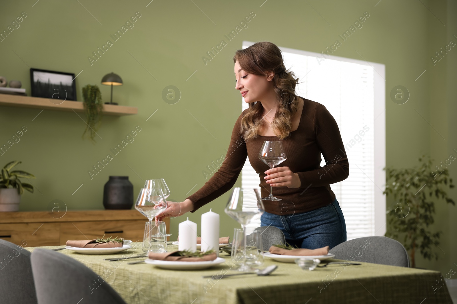 Photo of Young woman setting table for dinner at home