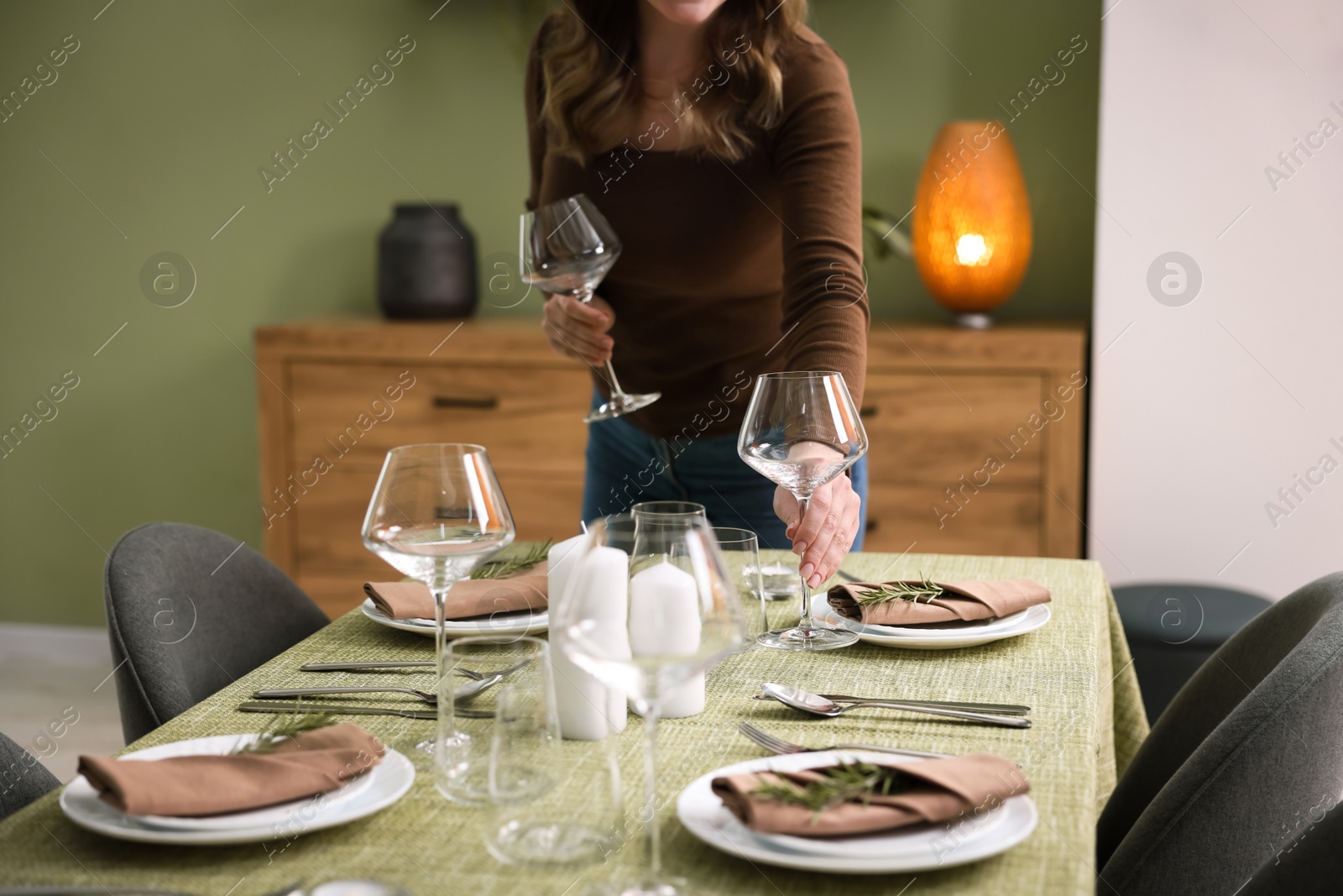 Photo of Young woman setting table for dinner at home, closeup