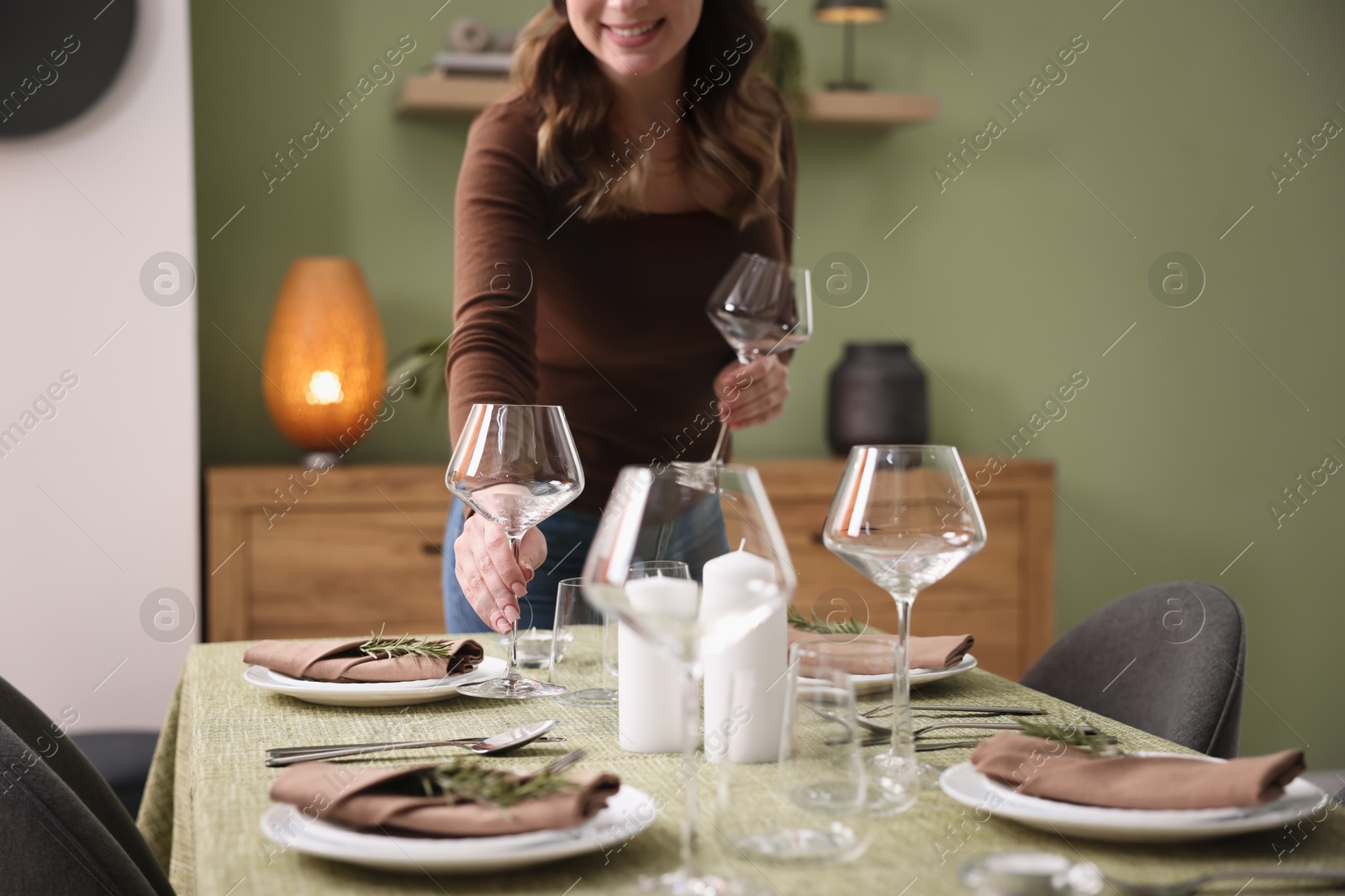 Photo of Young woman setting table for dinner at home, closeup