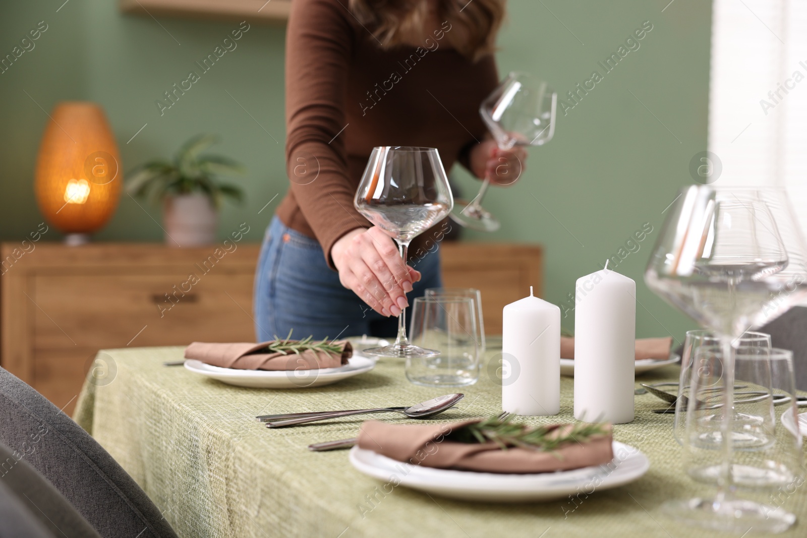 Photo of Young woman setting table for dinner at home, closeup