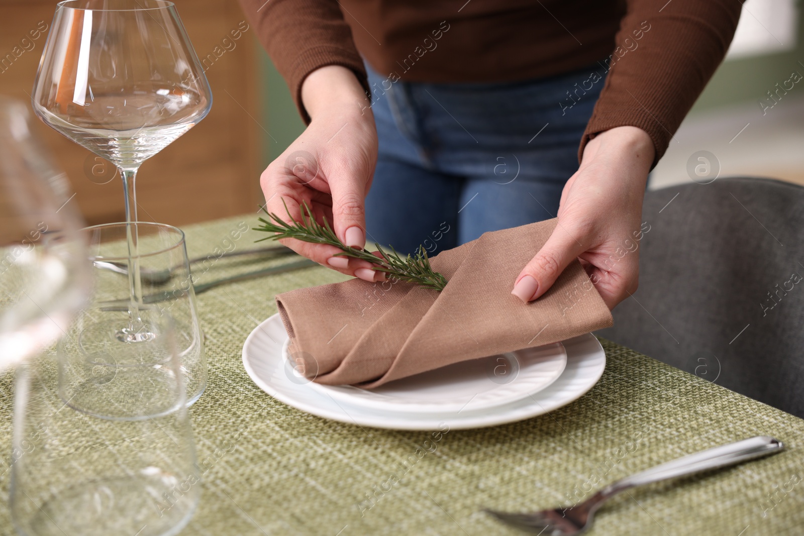 Photo of Young woman setting table for dinner at home, closeup