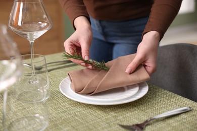 Young woman setting table for dinner at home, closeup