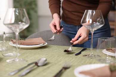 Young woman setting table for dinner at home, closeup