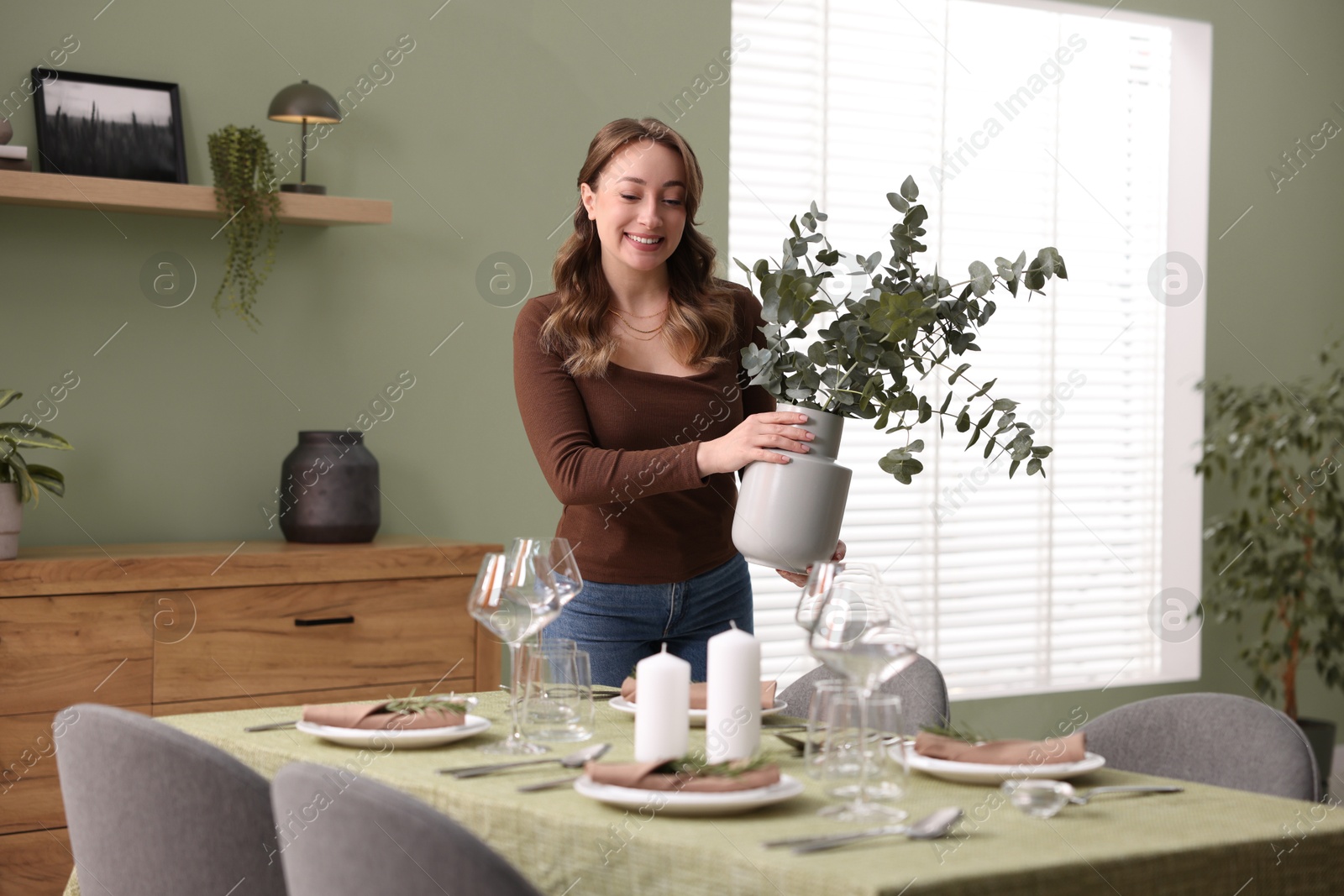 Photo of Happy young woman setting table for dinner at home