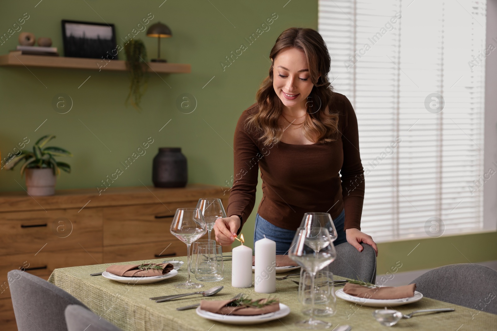 Photo of Happy young woman setting table for dinner at home