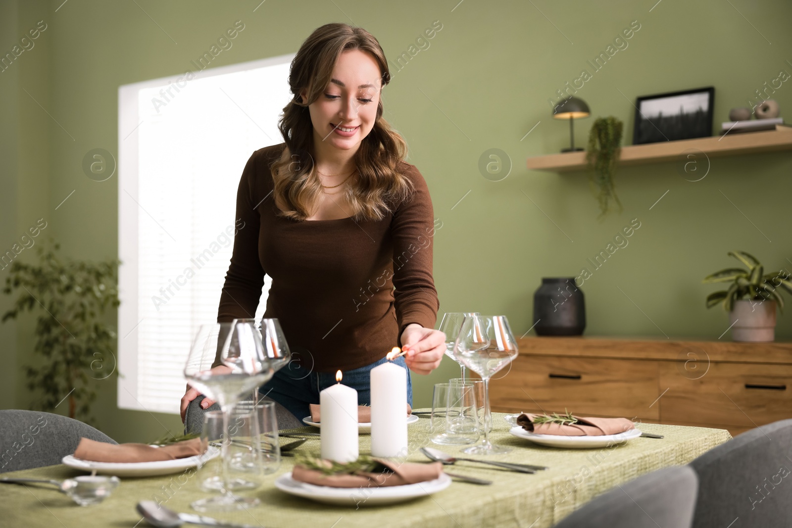 Photo of Happy young woman setting table for dinner at home