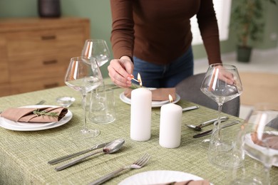 Photo of Woman lighting candles at table indoors, closeup