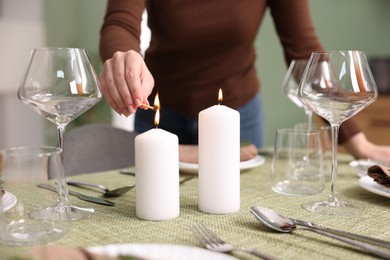 Photo of Woman lighting candles at table indoors, closeup