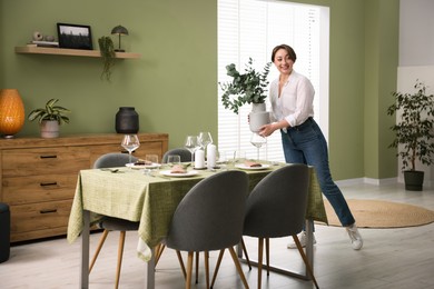 Photo of Happy young woman setting table for dinner at home