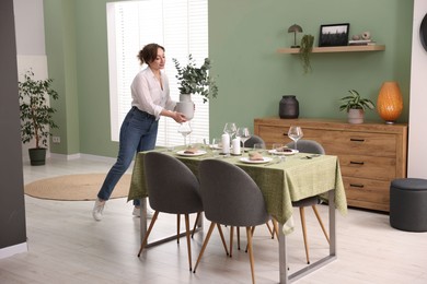 Photo of Young woman setting table for dinner at home