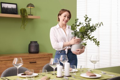 Photo of Happy young woman setting table for dinner at home