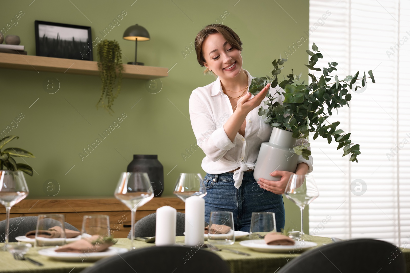 Photo of Happy young woman setting table for dinner at home